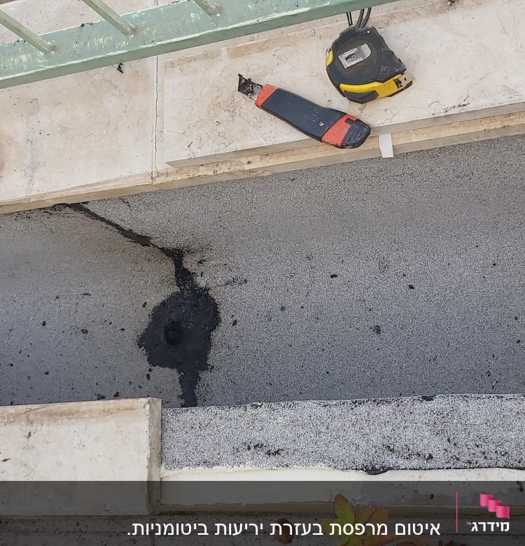 כלי עבודה וסרט מדידה על משטח אטום בזפת